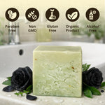 A rectangular bar of pale green soap stands on a white surface in front of a sink, styled with black roses and green leaves. Above the soap, five circular icons read 'Paraben Free', 'Non GMO', 'Gluten Free', 'Organic Product', and 'Alcohol Free'.