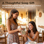 Two women smiling and exchanging a handmade soap bar in a warm, sunlit indoor setting. Text at the top reads, 'A Thoughtful Soap Gift: Handmade organic soap, a meaningful choice for personal or shared use.