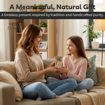 Two women sitting on a couch, one giving a gift to the other, with a cozy living room setting.