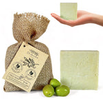 Dr. Ancient olive oil soap with a burlap bag and olives on a white background