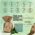 A bar of Dr. Ancient natural soap in a burlap pouch with a kraft paper tag, shown next to the cut soap bar and green leaves on a light green background with benefit icons and text.