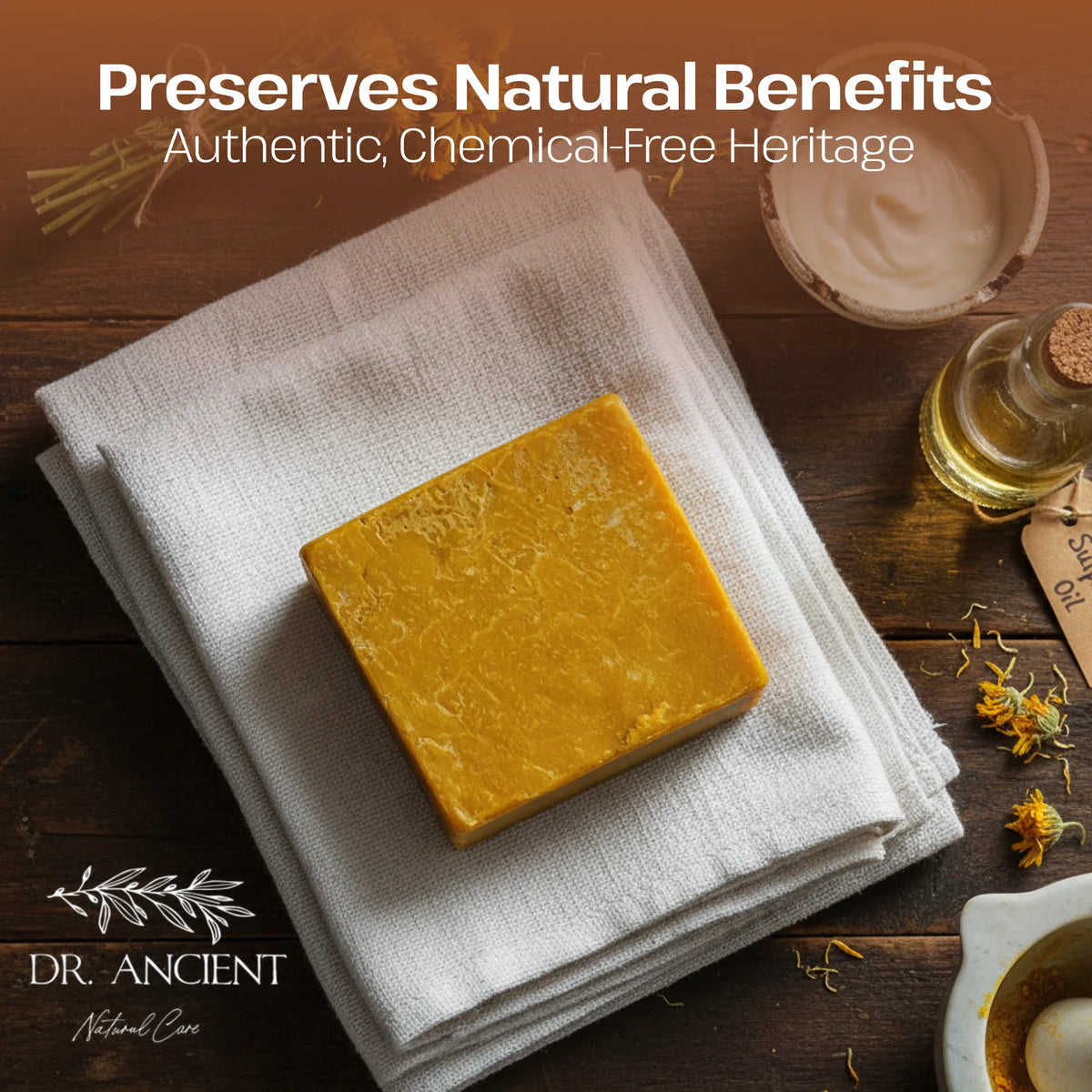 A rectangular bar of golden yellow handmade soap rests on a folded white linen cloth on a dark wooden surface. The scene includes a small glass bottle of oil, dried flowers, a bowl, and the text 'Preserves Natural Benefits' and 'DR.