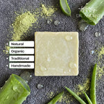 Bar of soap with aloe vera leaves and green powder on a dark background, featuring the brand 'Dr. Ancient'.