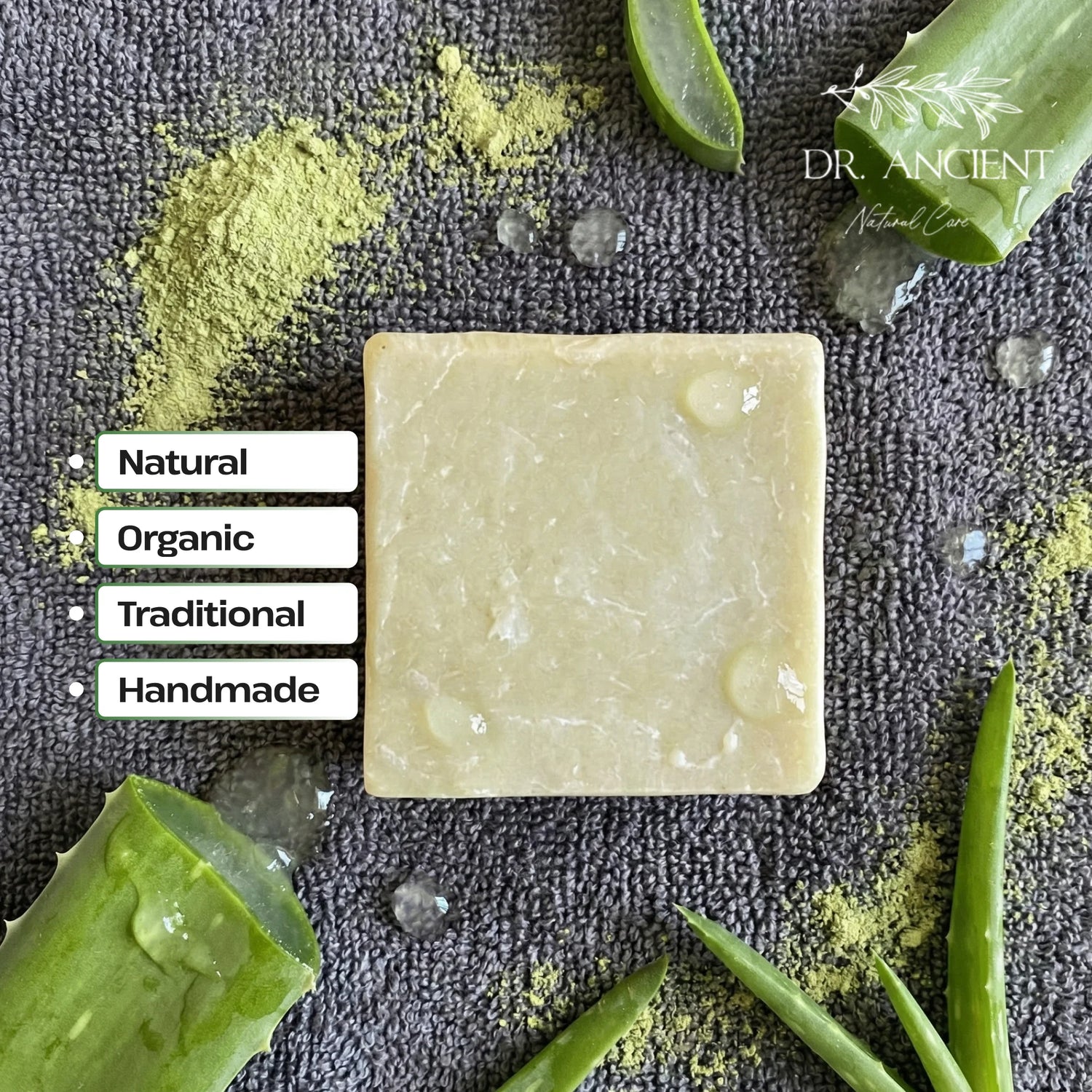 Bar of soap with aloe vera leaves and green powder on a dark background, featuring the brand 'Dr. Ancient'.