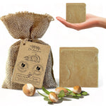 Dr. Ancient argan soap with packaging, a hand holding a bar of soap, and argan nuts on a white background.