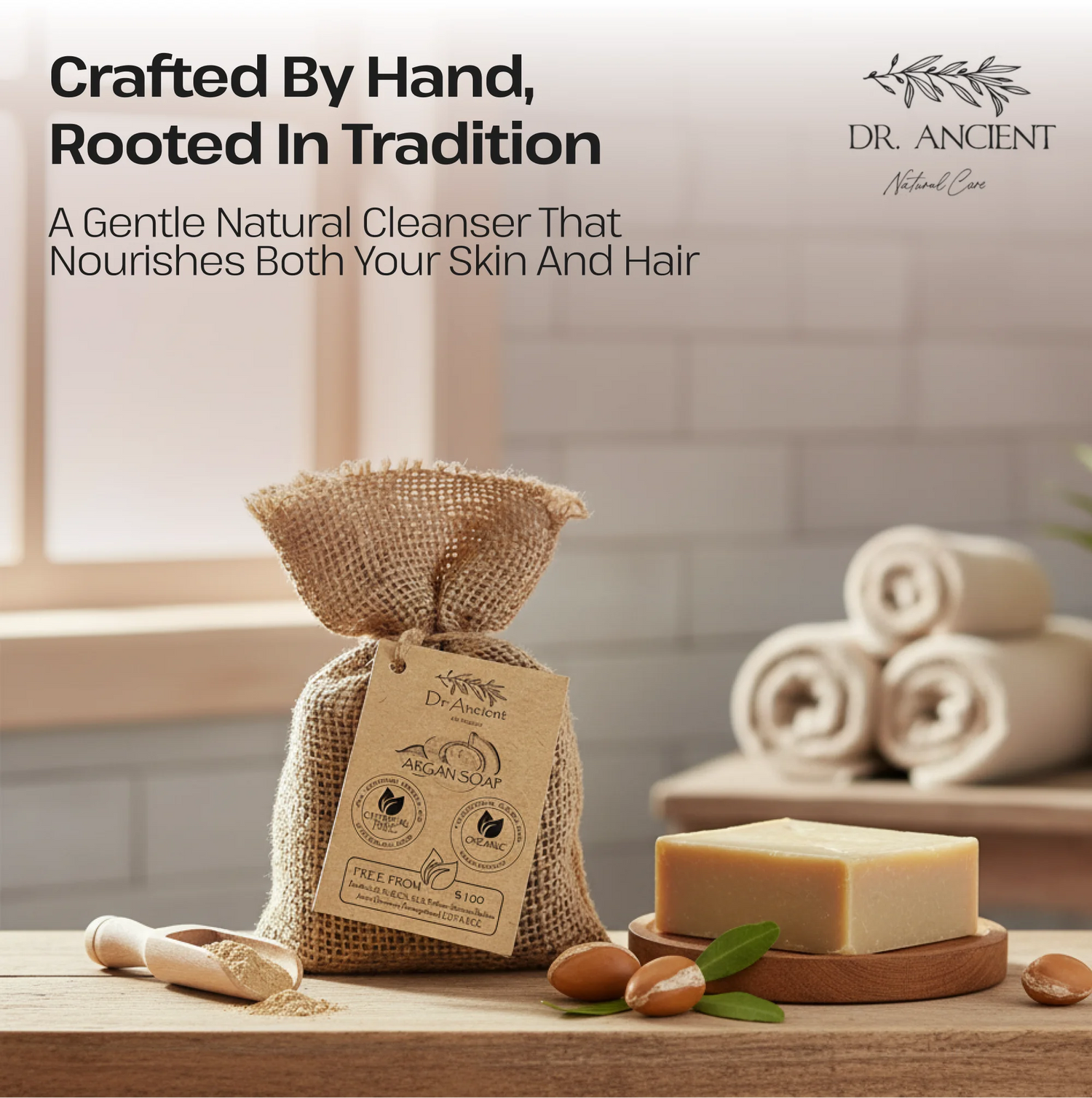 A burlap drawstring pouch labeled Dr. Ancient Rice & Plant-Based Cleanser sits on a wooden table in a softly lit bathroom setting, with a bar of soap, rolled towels, and nuts nearby.