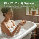 A woman in a bubble bath holds an orange bar soap bar, with promotional text at the top reading 'Kind To You & Nature' and 'Crafted With Olive & Wild Pistachio For Skin & Hair Wellness.' The brand 'DR.