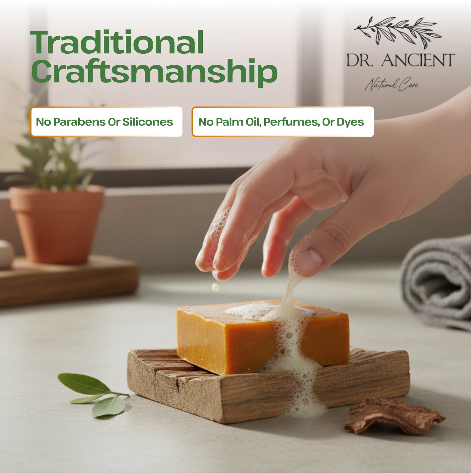 A hand is washing a bar of soap on a wooden soap dish, with a small plant and rolled towel in the background. Text on the image reads 'Traditional Craftsmanship' and 'No Parabens Or Silicones' and 'No Palm Oil, Perfumes, Or Dyes.