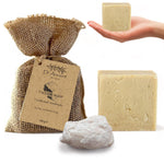 Dr Ancient tallow soap with packaging, a hand holding a bar of soap, and a white stone on a white background.
