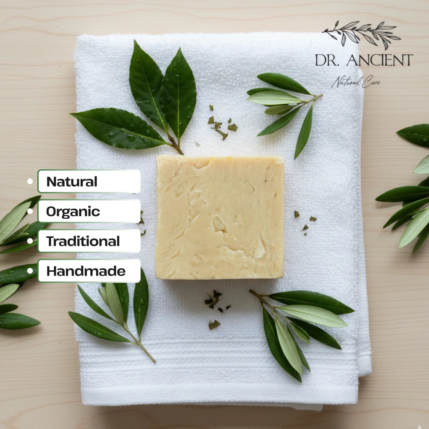 Block of soap on a white towel with green leaves, labeled as natural, organic, traditional, and handmade by Dr. Ancient.