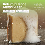 Bar of soap with foam, labeled 'Naturally Clear, Gently Clean' by Dr. Ancient, on a dark surface.